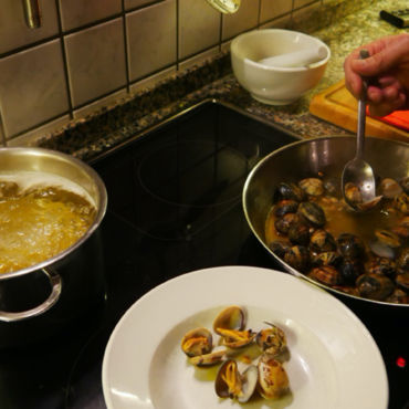 Zubereitung einer Muschel Pasta. Die Pasta wird in einem Topf gekocht und die Muscheln in einer Pfanne zubereitet.